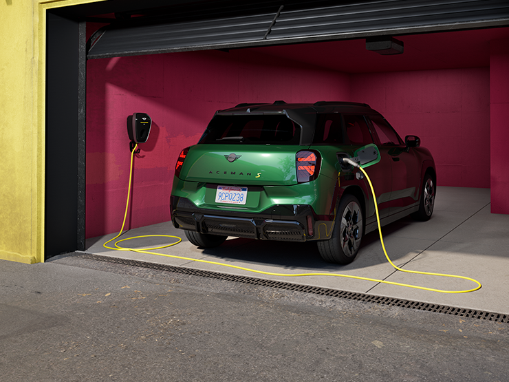 Rear view of the all-electric MINI Aceman in British Racing Green charging in a garage. 